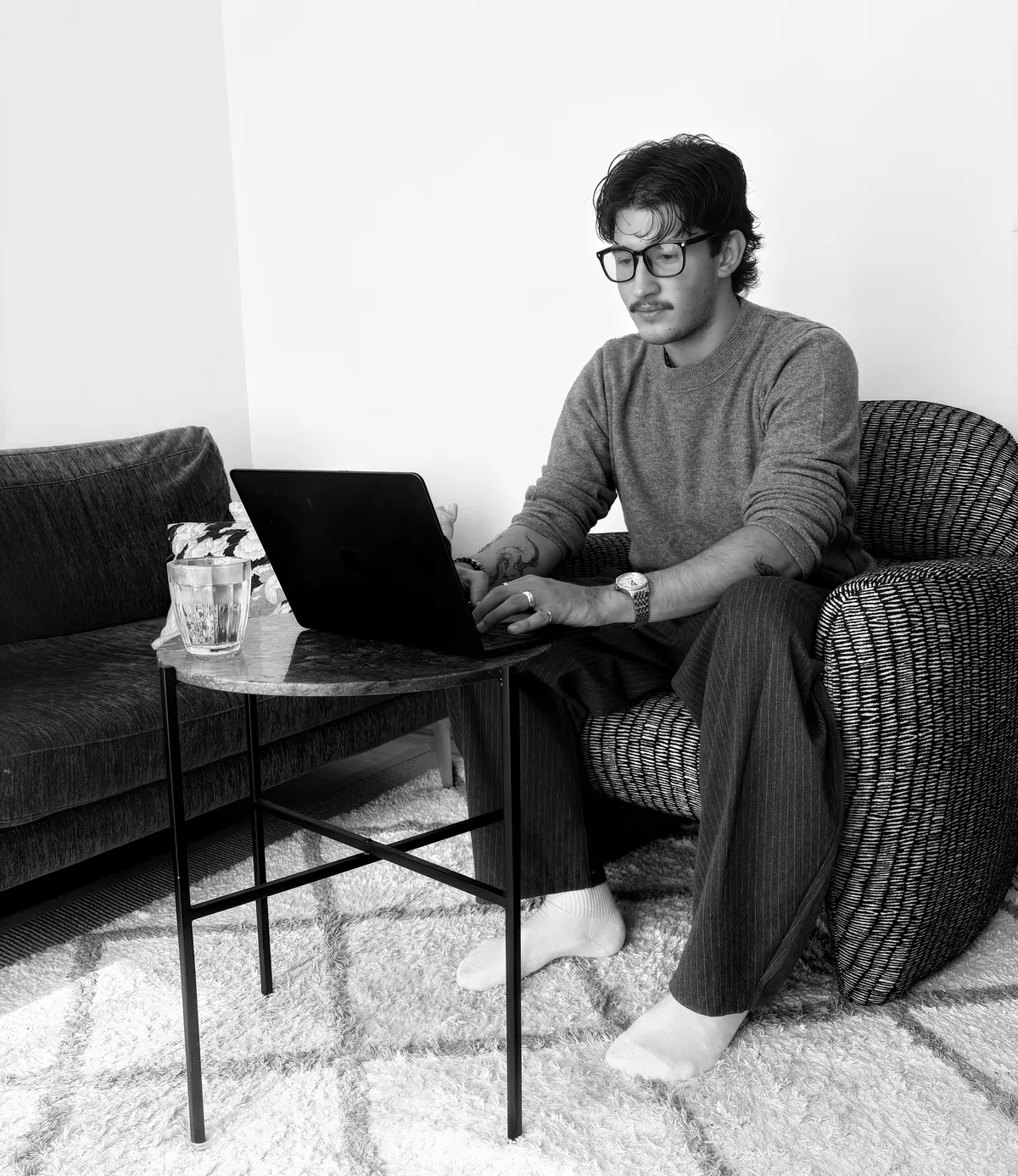 Frederic am Laptop, in einem Sessel neben einem kleinen runden Tisch